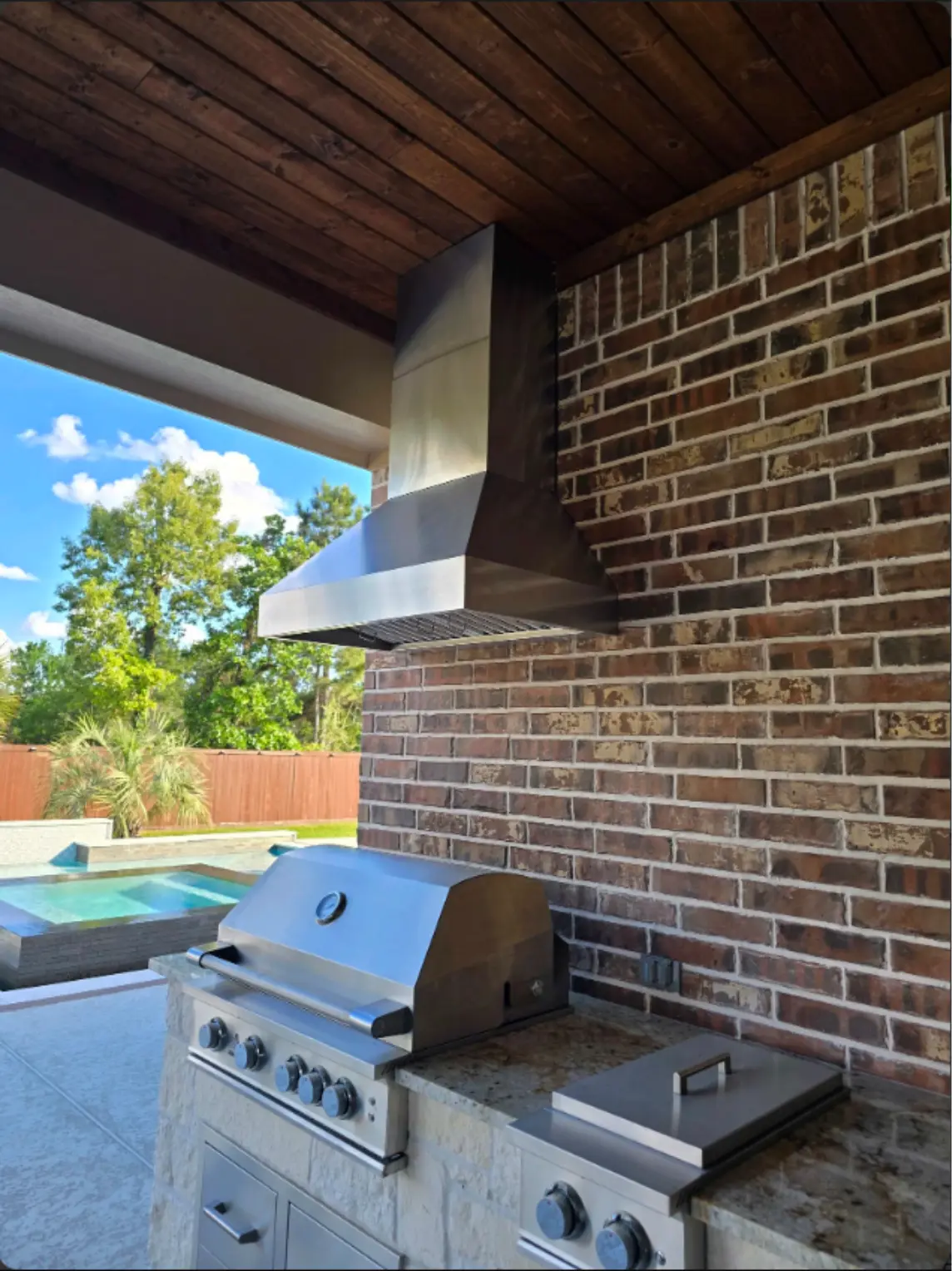 Built-in stainless steel BBQ grill under a covered patio