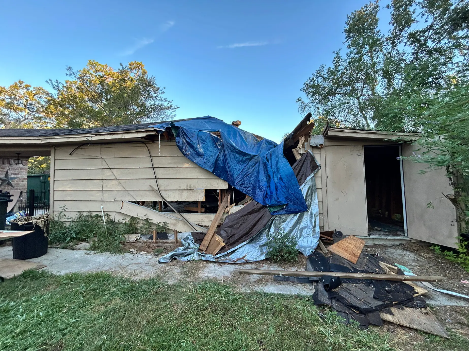 Emergency tarp over storm-damaged roof and siding on a Conroe home
